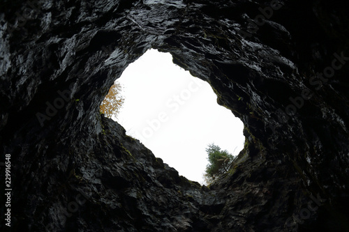 View of the sky and trees from the bottom of a stone mine
