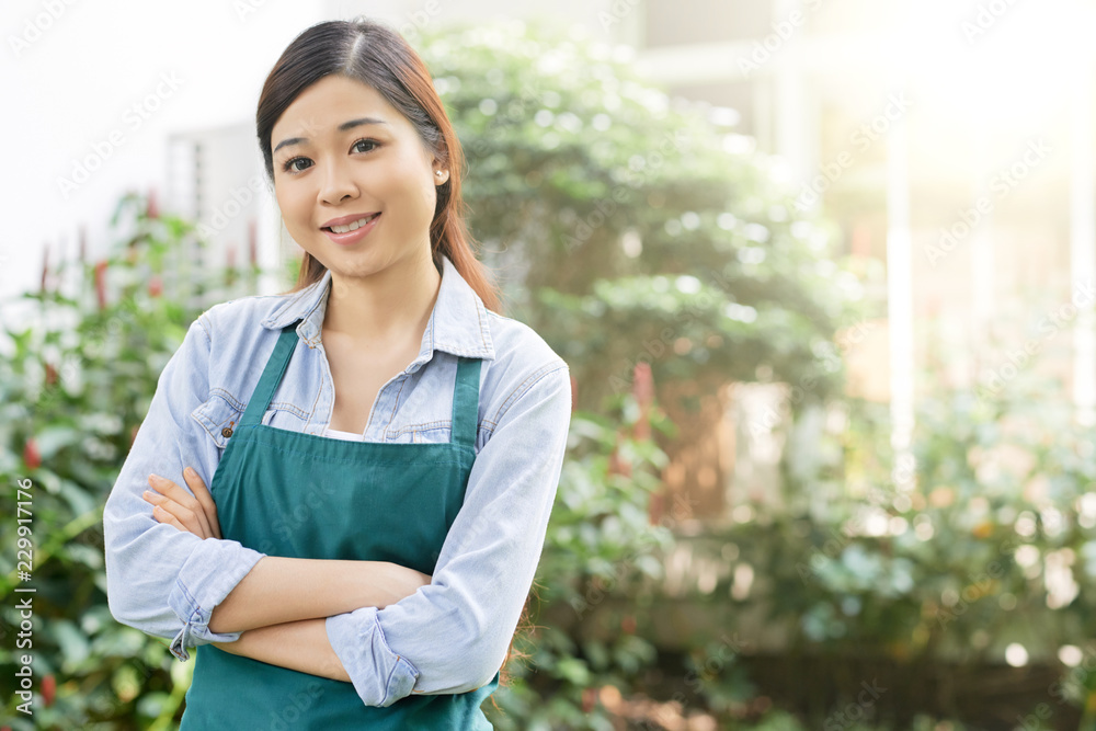 Portrait of Asian smiling woman standing outdoors with green trees in the background Portrait of Asian smiling woman standing outdoors with green trees in the background