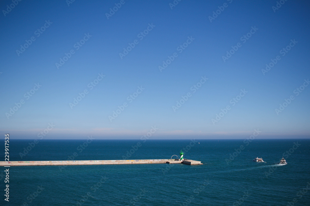 Breakwater in port with two boats in the background