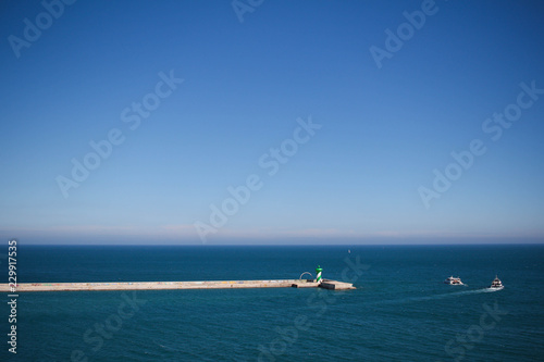 Breakwater in port with two boats in the background © Marta
