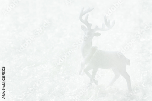 White deer standing in snow forest. Magic winter scene. Christmas New Year greeting card poster banner in monochrome. Minimalist creative image in scandinavian style. Copy space for text.