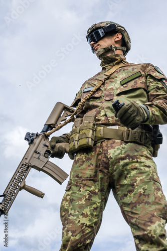 military man holding automatic rifle and hand grenade photo