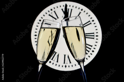 CELEBRATION OF THE NEW YEAR, glasses raising with champagne with the clock unfocussed photo