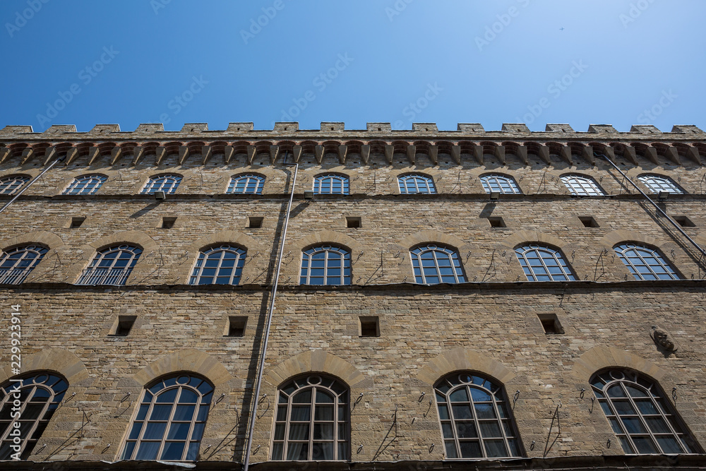 Looking up at a building in Florence with a crenellated roof line; Florence, Tuscany, Italy