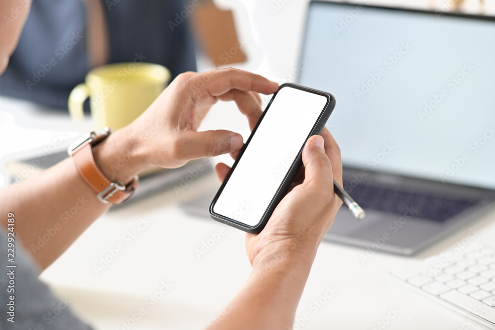 Cropped shot of businessman hand holding blank screen mobile phone at office Cropped shot of businessman hand holding blank screen mobile phone at office