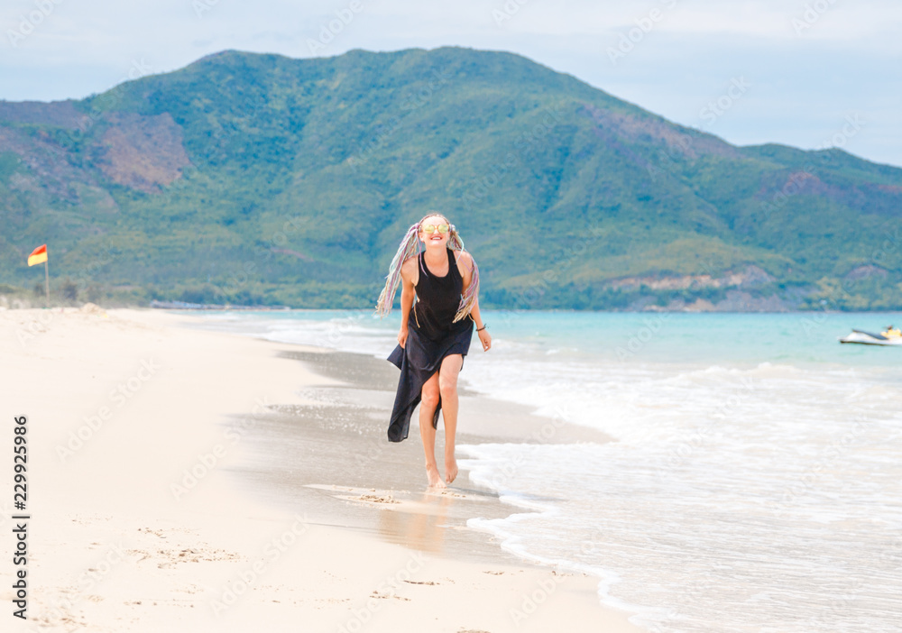 beautiful girl in a black dress walks on the beach