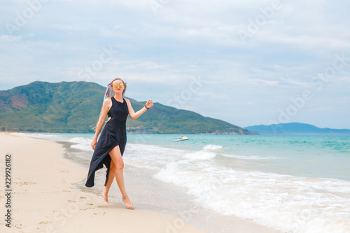 beautiful girl in a black dress walks on the beach