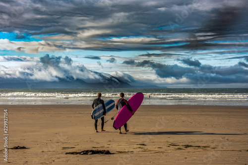 Surfers going into the Ocean in Inch Strand, Kerry County, Ireland