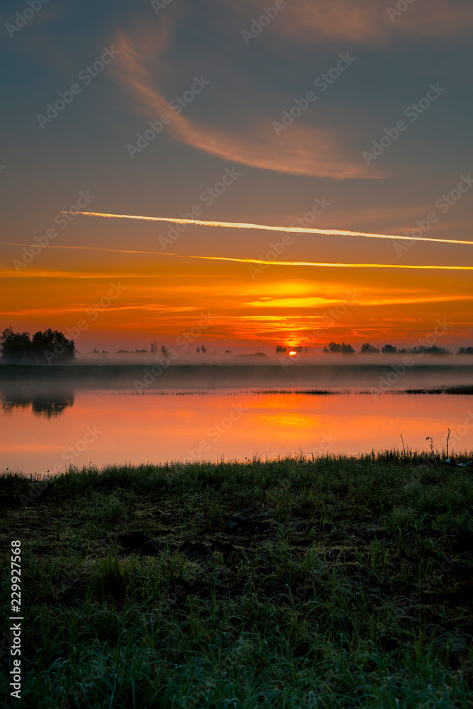 Dawn over a small river on a foggy morning