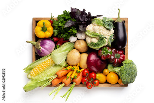 Fresh organic vegetables in wooden box on white