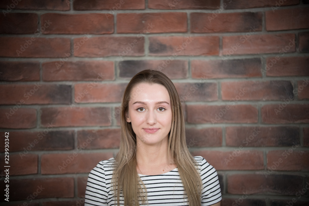 Portrait of young beautiful girl with long hair on brick wall background Portrait of young beautiful girl with long hair on brick wall background