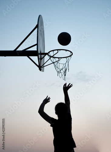Silhouette of a young girl shooting a basketball 