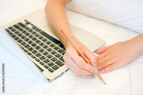 write paper note on the bed by close up hand woman on bed and laptop in vacation day