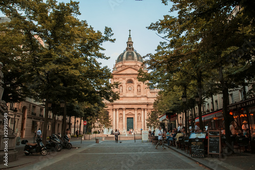 Fototapeta Naklejka Na Ścianę i Meble -  View of the University of Paris Sorbonne between the trees. Sorbonne Square with tourists and restaurants.