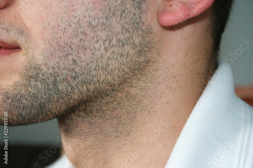 A man's face with a slight beard. A few days beard on the guy's chin. Macro picture taken from the profile. photo