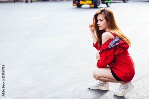 Travelers Asian woman wearing a white long-sleeved casual wear red. Sitting on the street at Yaowarat Road in Bangkok, Thailand.
