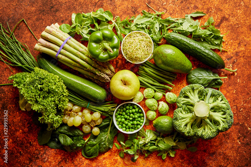 Fresh, natural, green vegetables, fruits and herbs assortment placed on a rusty metal background. Top view.