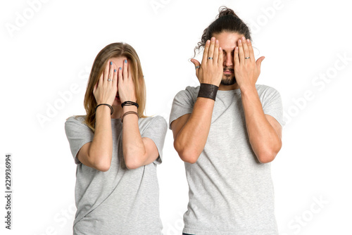 Couple covered their eyes. Man and a woman put their hands over their eyes together on white background. Close your eyes.
