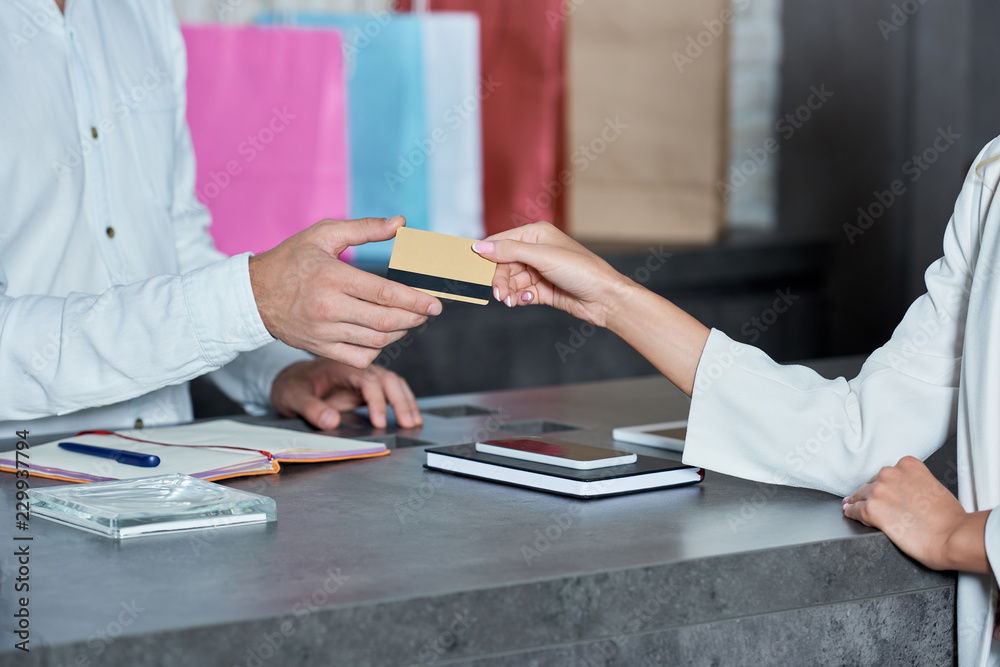 cropped shot of customer giving credit card to salesman in shop cropped shot of customer giving credit card to salesman in shop
