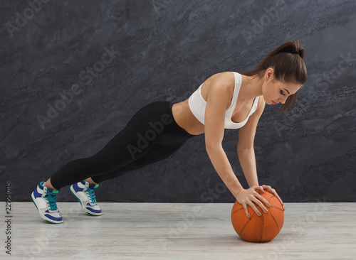Fitness woman plank training at grey background indoors © Prostock-studio