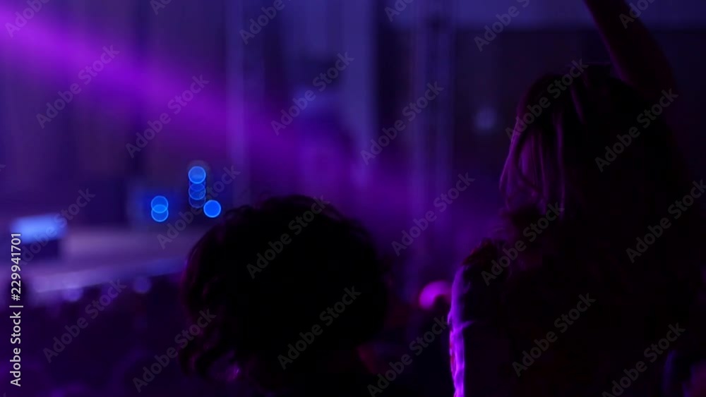 Dancing girl fan silhouettes on a concert flashing light cheerful hands in air
