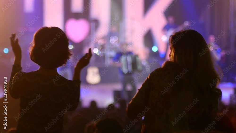 Dancing girl fan silhouettes on a concert flashing light