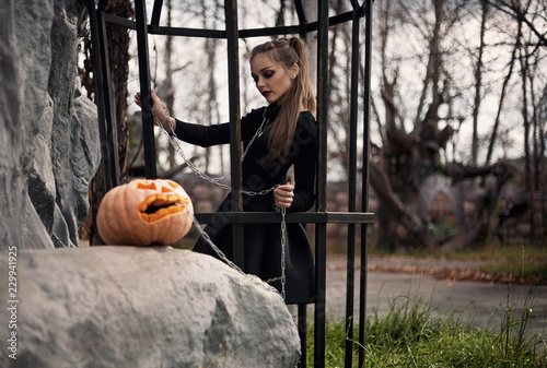 A girl with beautiful make-up walks a hand-pumpkin on a leash in a fabulous park. Halloween creative picture