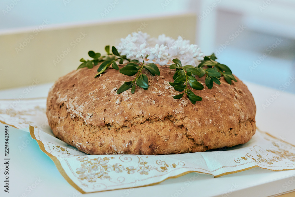 Fresh homemade cereal round bread decorated with green on white background