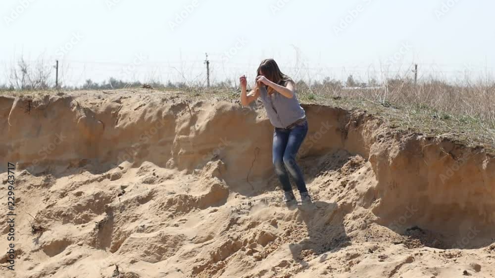 A young girl has fun jumping on the sand dunes in the desert A young girl has fun jumping on the sand dunes in the desert