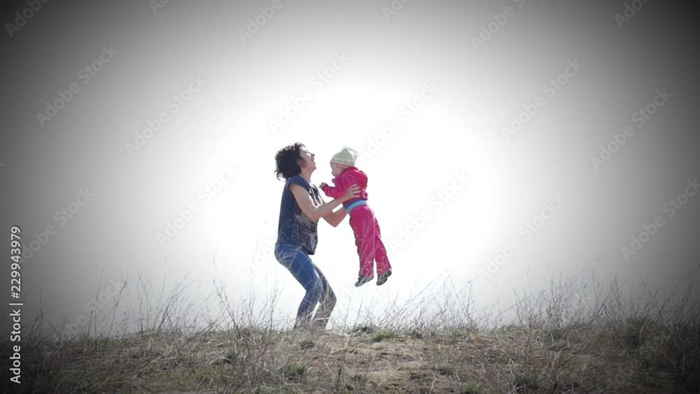 Mother throws baby up in the air against the sky Mother throws baby up in the air against the sky