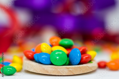 colorful chocolate buttons in a wooden spoon on a white background
