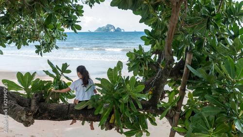 teenager sitting on tree at beach