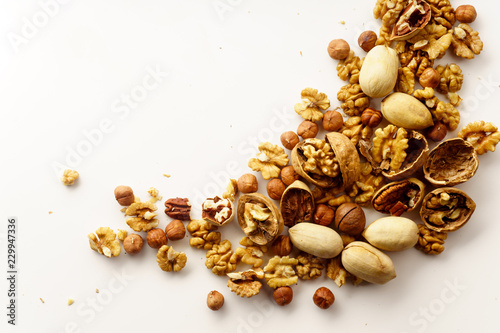 Overhead image of a group of various nuts with nutshells isolated on white background with copy space