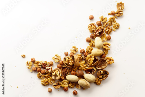 Overhead image of a group of various nuts with nutshells isolated on white background with copy space