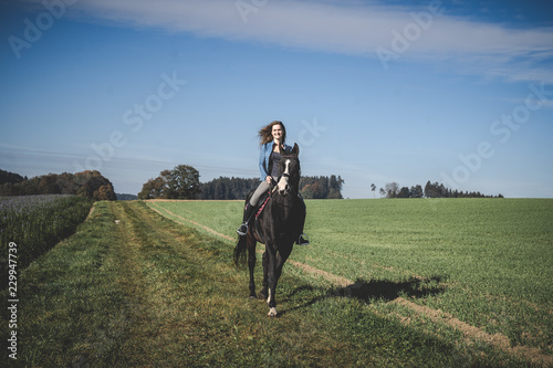 Junge schöne Frau und schwarzes Pferd Ausritt, reiten, Derssur, Reiterin © Christina