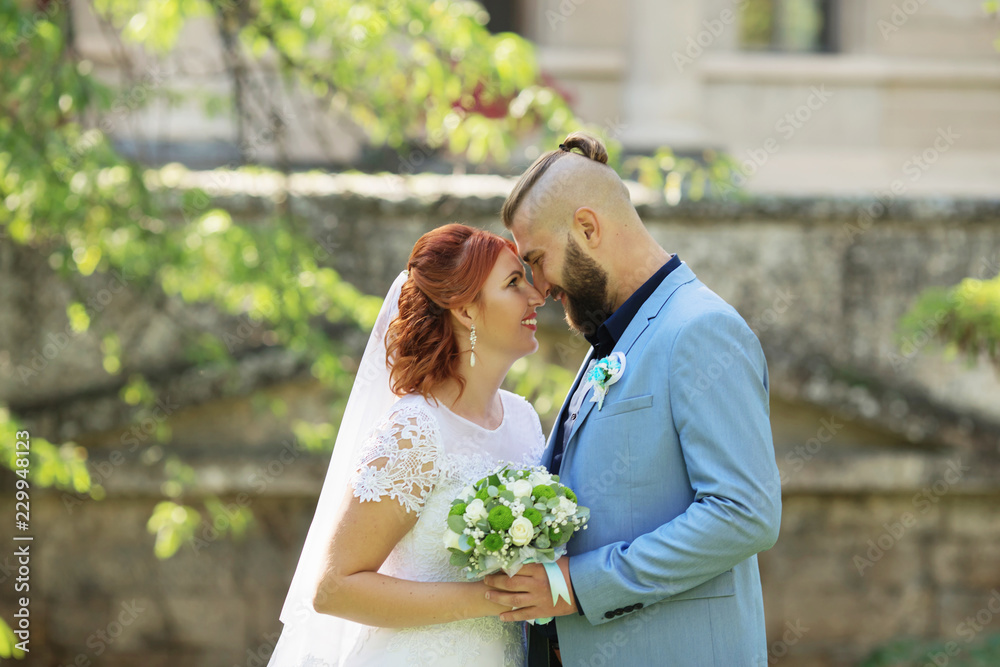 Naklejka premium Just married loving hipster couple in wedding dress and suit in the park. Happy bride and groom walking running and dancing. Romantic Married young family.