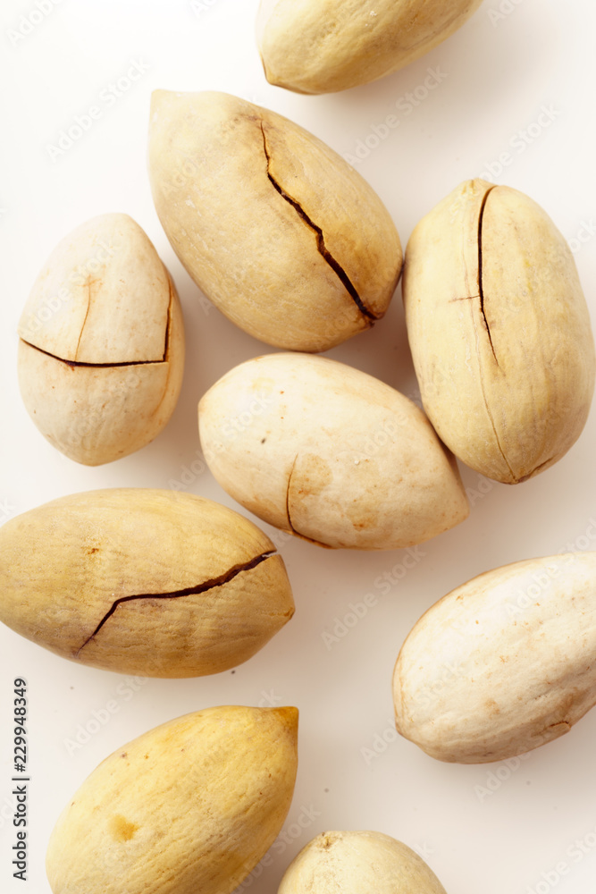 Obraz premium Pecan nuts in nutshells isolated. Overhead image, white background