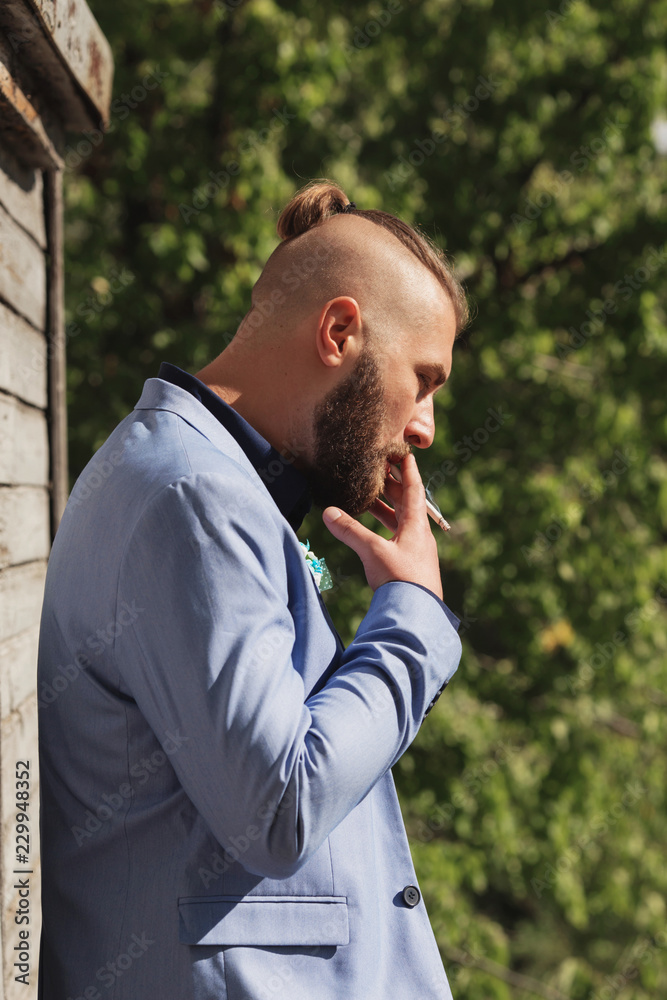 hipster young man looking away from the camera while smoking a cigarette. hipster young man looking away from the camera while smoking a cigarette.