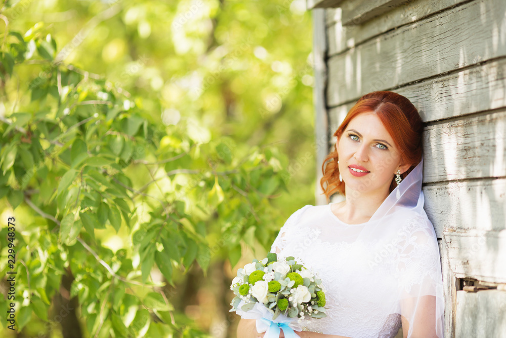 Beautiful redhead bride with bouquet outdoor. Happy bride outdoors. Beautiful bride posing in her wedding Beautiful redhead bride with bouquet outdoor. Happy bride outdoors. Beautiful bride posing in her wedding