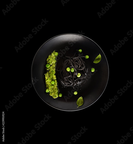black spaghetti with green peas on a black plate