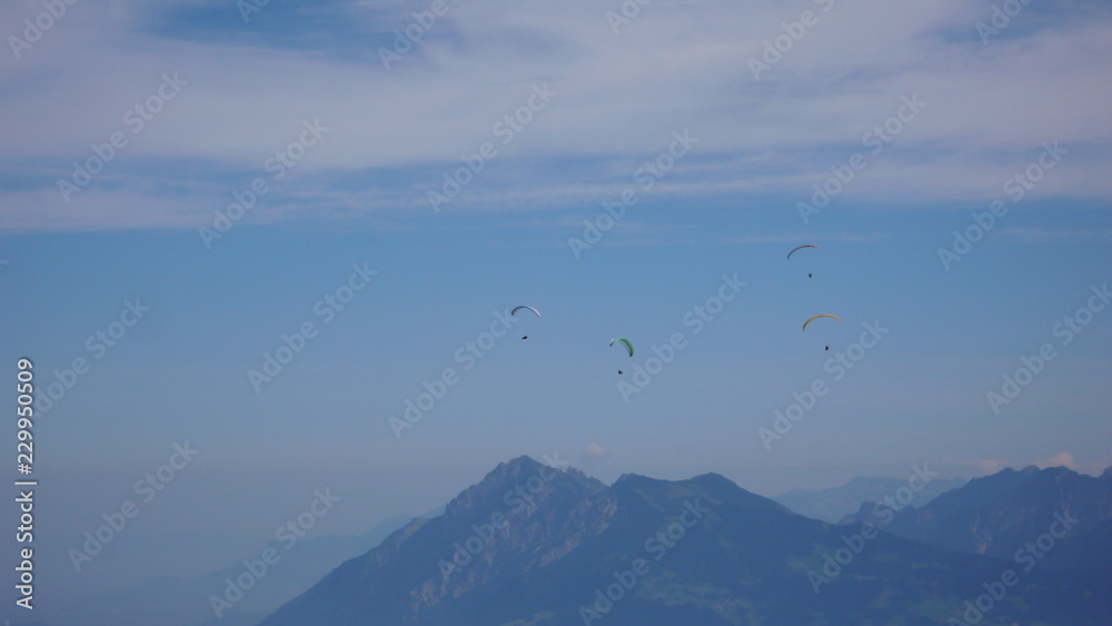 paragliders flying in the sky above the mountains of Switzerland