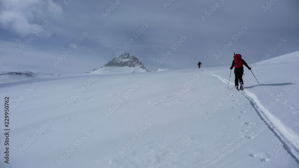 backcountry skiers on a climb in the Hohen Tauern region of the Austrian Alps putting in new tracks on their way to a distant mountain peak