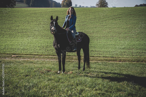 Junge schöne Frau und schwarzes Pferd Ausritt, reiten, Derssur, Reiterin