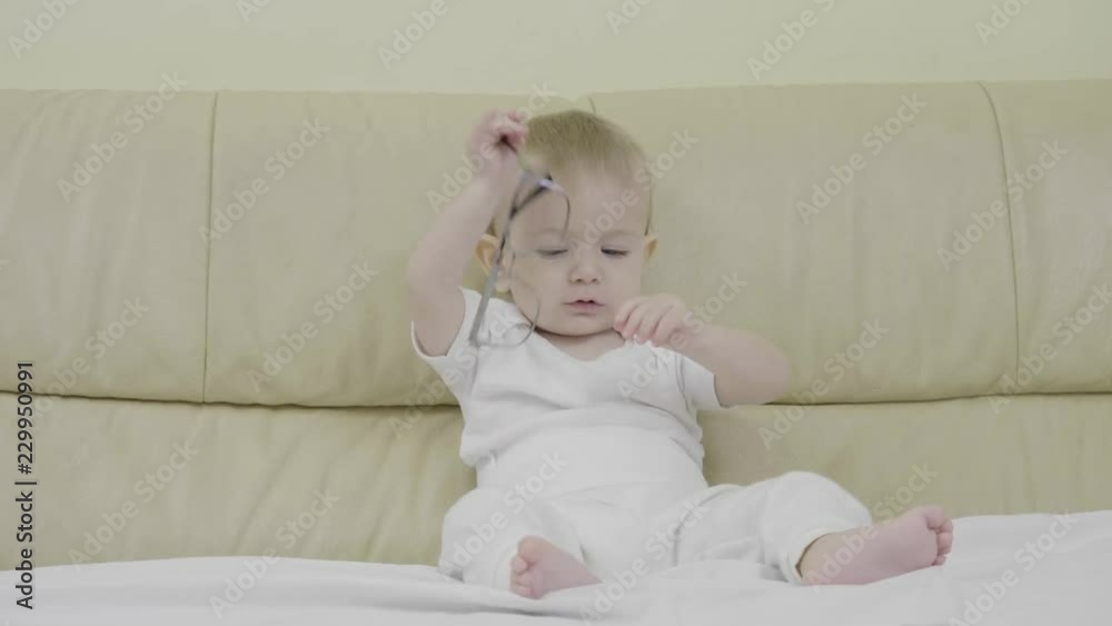 Funny baby playing with eyeglasses, child eat eyeglass 