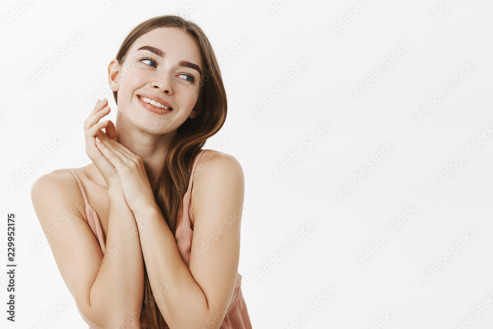 Waist-up shot of sensual gentle and feminine european woman holding hands  together near shoulders tilting head and gazing with admiration and  affection right smiling flirty over white background Stock Photo