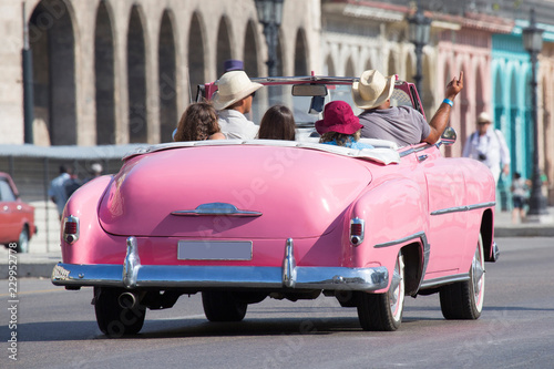 Schöner rosa Oldtimer/Cabriolet mit fröhlicher Gruppe auf Kuba (Karibik) photo