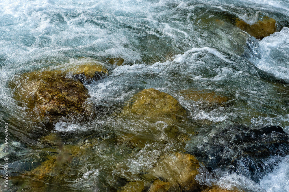 Obraz premium Powerful flow of water over the stones, mountain river close up.