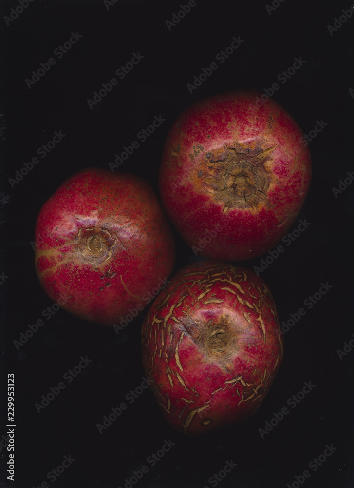 Three pomegranates aginst dark background Three pomegranates aginst dark background
