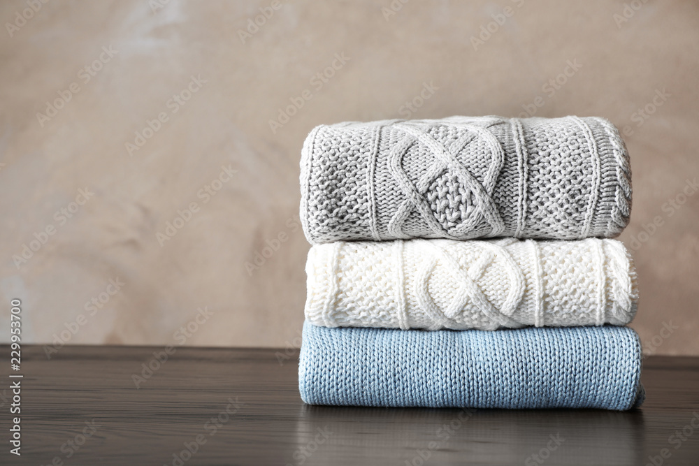 Stack of folded knitted sweaters on table. Space for text Stack of folded knitted sweaters on table. Space for text
