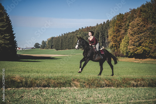 Junge schöne Frau und schwarzes Pferd Ausritt, reiten, Derssur, Reiterin